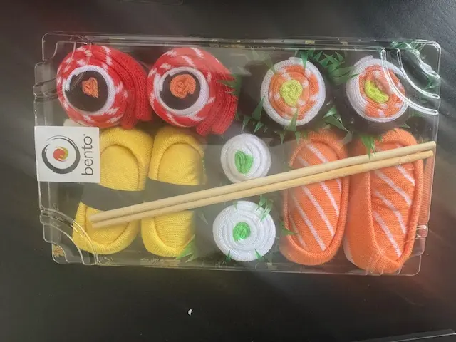 Bento sushi-themed socks arranged like pieces of sushi in a gift tray