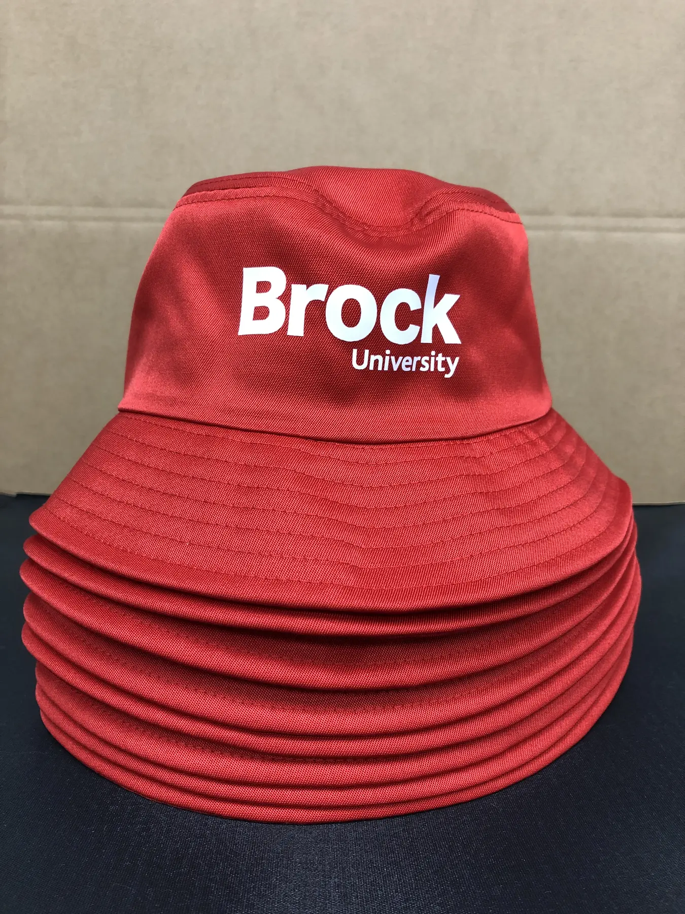Stack of red Brock University embroidered bucket hats