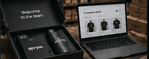 A premium welcome kit and luxury packaging beside a laptop showing a branded company store, warehouse behind